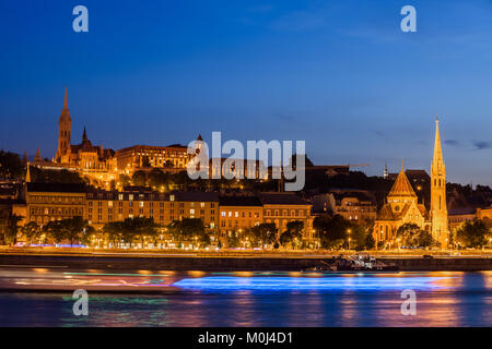 Città di Budapest di notte, crociera barche sentieri di luce sul fiume Danubio, skyline del lato di Buda, Ungheria. Foto Stock