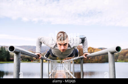 Giovane uomo con lo smartphone facendo esercizio nel parco. Foto Stock