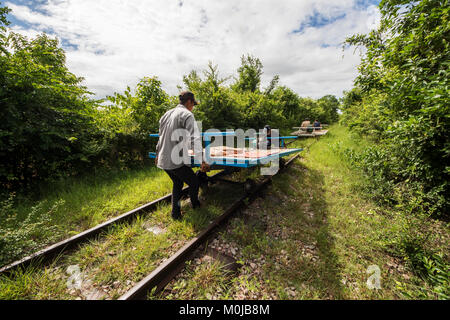 Gli uomini posizionando la piattaforma di bambù sulle ruote del Norry, bamboo treno; Battambang, Cambogia Foto Stock