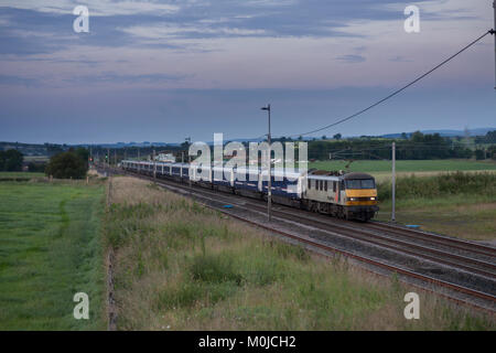 Il 2350 London Euston - Glasgow & Edinburgh Caledonian sleeper passa Plumpton (nord di Penrith) presto su una mattina estati Foto Stock