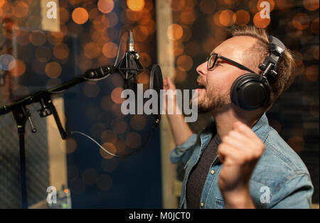 Uomo con cuffie cantando in studio di registrazione Foto Stock