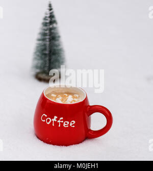 Rosso tazza ceramica con caffè e marshmallows sul bianco della neve Foto Stock