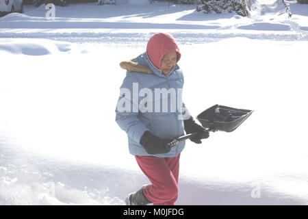 Lady nella neve profonda, con pala, pronto a pala di neve da passo carraio dopo una tempesta di neve. Foto Stock