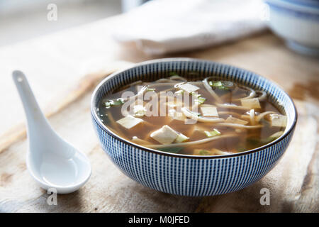 Ciotola di rosso la zuppa di miso con tofu, i cipollotti e udon tagliatelle e zuppa di bianco cucchiaio. Foto Stock