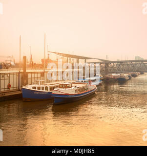 Amburgo, Germania- Agosto 14, 2015: Tramonto ad Amburgo in una nebbiosa sera dal fiume Elba con attrezzi trainati navi passeggeri, tonica immagine panoramica Foto Stock
