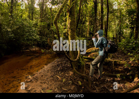 Un fotografo di natura delle pause per fotografare qualcosa nella foresta amazzonica. Foto Stock