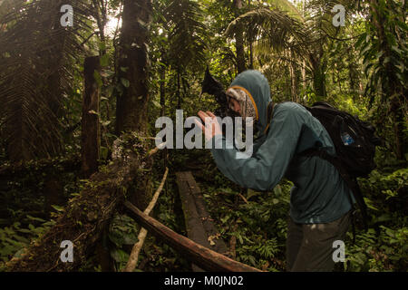 Un fotografo di natura delle pause per fotografare qualcosa nella foresta amazzonica. Foto Stock