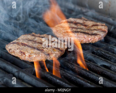 Due pezzetti di carne di pollo Burger bistecche alla griglia con fiamme. La cottura di pollo o grill barbecue barbecue o su carboni di legna. Close up Foto Stock