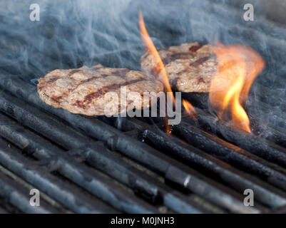 Due pezzetti di carne di pollo Burger bistecche alla griglia con fiamme. La cottura di pollo o grill barbecue barbecue o su carboni di legna. Close up Foto Stock