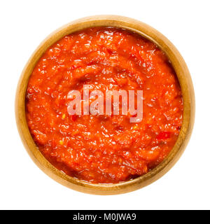 Ajvar nella ciotola di legno. Condimento fatto di peperoni, utilizzati in cucina balcanica. La diffusione del pane o sul lato piatto. Chiamato anche il serbo o insalata di caviale vegetale Foto Stock