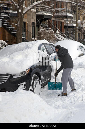 L'uomo prendendo la neve fuori la sua auto in inverno Foto Stock