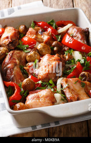 Dieta organici cibo: coniglio al forno con funghi, pepe e cipolle close-up in una teglia su una tavola verticale. Foto Stock