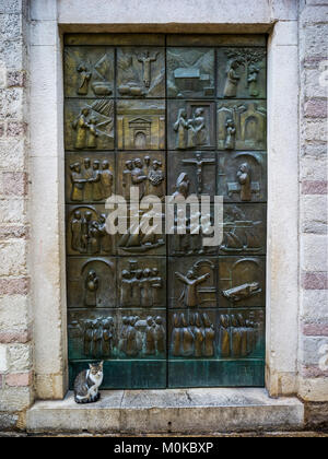 Una porta metallica con pittogrammi posti in piazze oltre la superficie e un gatto seduto sul gradino; Montenegro Foto Stock