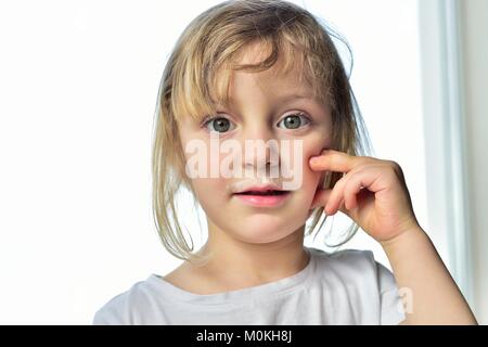 Close up divertente ritratto di carino bambina con latte baffi. Ritratto di un po' di felice ragazza con yogurt sulla faccia. Foto Stock