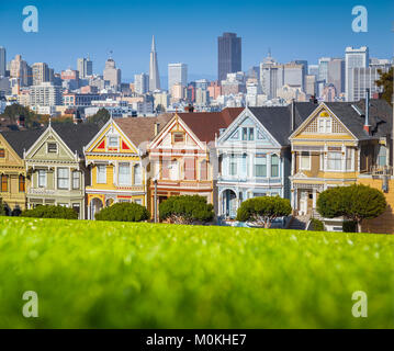 Famosa Painted Ladies, una fila di colorate case in stile vittoriano situato presso Scenic Alamo Square, con lo skyline di San Francisco al tramonto, CALIFORNIA, STATI UNITI D'AMERICA Foto Stock