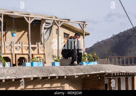 Masuleh, IRAN - 22 dicembre 2017 un uomo sul bordo del tetto, villaggio di montagna nella provincia di Gilan Foto Stock