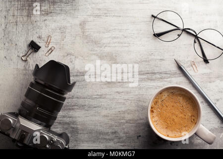 Specchio della fotocamera in meno, una tazza di caffè caldo con schiuma e bicchieri in legno tabella squallido. Al mattino il concetto di pianificazione, vista dall'alto, spazio di copia Foto Stock