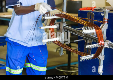 Riavvolgimento di un motore elettrico, uomo africano al lavoro Foto Stock