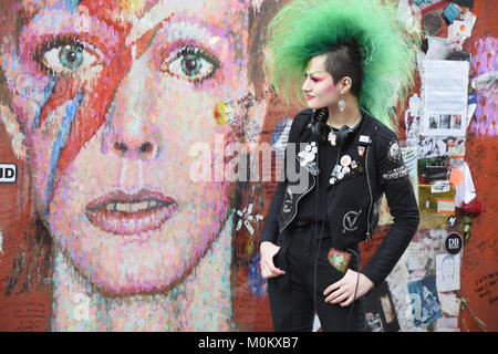 La signora punk si pone accanto al murale di Aladdin Sane a Brixton, nel secondo anniversario della morte di David Bowie il 10.01.2016, Brixton, London.UK Foto Stock