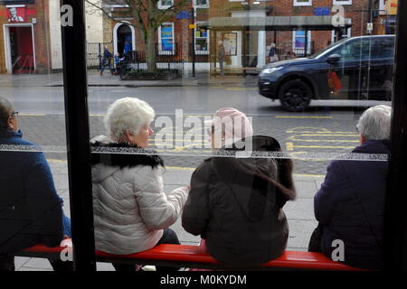 I pensionati sit in chat con un bus shelter in attesa di un autobus in Brentwood Essex su una fredda mattina Foto Stock