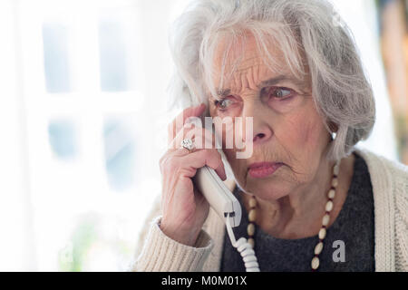 Preoccupato Senior donna rispondendo Telefono in casa Foto Stock