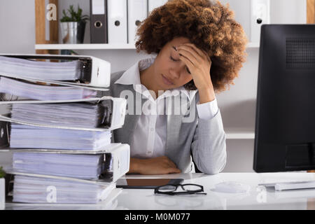 Stressante Afro American imprenditrice seduta in ufficio con impilati di file Foto Stock