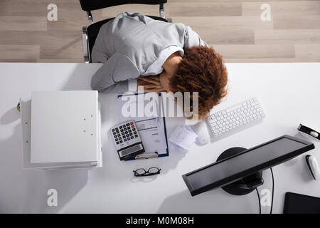 Sottolineato imprenditrice dormire in ufficio con impilati di file e calcolatrice Foto Stock