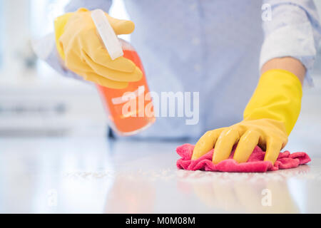 Close up della donna utilizzando spray polacco di pulire la superficie da cucina Foto Stock