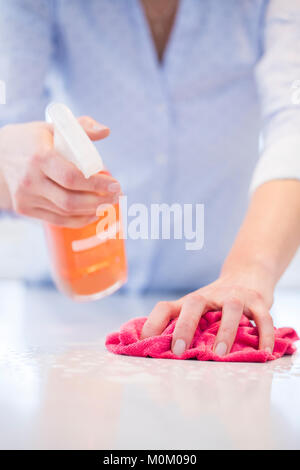 Close up della donna utilizzando spray polacco di pulire la superficie da cucina Foto Stock