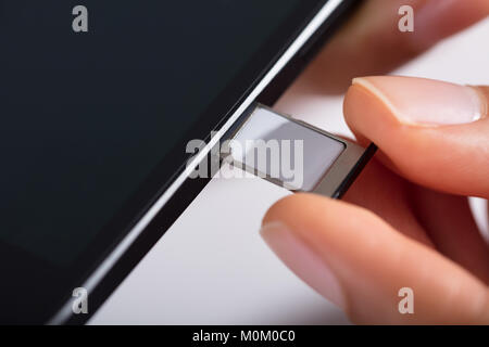 Close-up di persona della mano inserire Micro SIM nel telefono cellulare Foto Stock