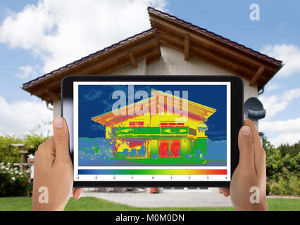 Close-up di persona a rilevare la perdita di calore al di fuori della casa usando la tavoletta digitale Foto Stock