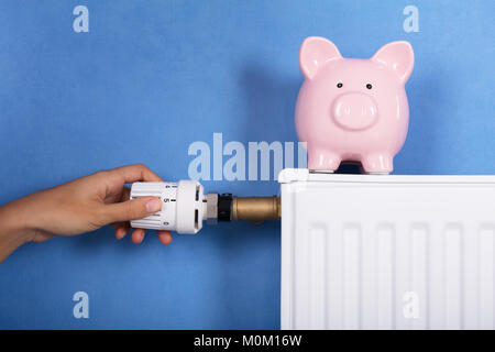 Persona Lato regolazione della temperatura sul termostato per risparmiare denaro sulla bolletta energetica Foto Stock