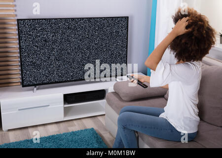 Giovane donna seduta su un divano vicino la televisione mostra nessun segnale Foto Stock