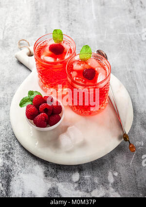 La bevanda alcolica con liquore di lampone e ghiaccio. due bicchieri di cocktail rinfrescante con bacche e foglie di menta. la bevanda alcolica con liquore di lampone e mi Foto Stock