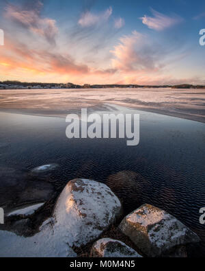 Paesaggio panoramico con il tramonto e il congelamento del lago alla sera d'inverno in Finlandia Foto Stock