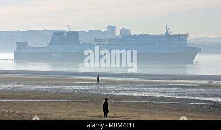 Una leggera foschia marina sorge dal Mersey come il traghetto da Liverpool a Dublino passa Antony Gormley è un altro luogo in Crosby il Merseyside. Foto Stock