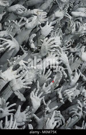 Armonici di sculture di una moltitudine di mani fino a raggiungere il cielo di fronte il bianco tempio Wat Rong Khun in Chiang Rai, Thailandia. Foto Stock