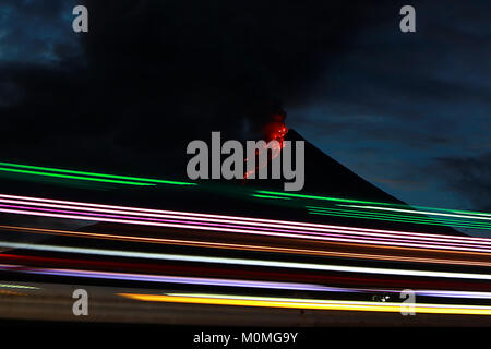 Albay, Filippine. 23 gen 2018. Sentieri di luce di passaggio di veicoli sono visti vicino al vulcano Mayon come scoppia nella provincia di Albay, Filippine, 23 gennaio, 2018. Il monte Vulcano Mayon nelle Filippine hanno continuato a fuoriuscire la lava e enormi pennacchi di fumo martedì poiché le autorità avvertono di un enorme e violenta eruzione entro giorni. Credito: Rouelle Umali/Xinhua/Alamy Live News Foto Stock