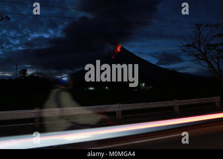 Albay, Filippine. 23 gen 2018. Sentieri di luce di passaggio di veicoli e un automobilista sono visti vicino al vulcano Mayon come scoppia nella provincia di Albay, Filippine, 23 gennaio, 2018. Il monte Vulcano Mayon nelle Filippine hanno continuato a fuoriuscire la lava e enormi pennacchi di fumo martedì poiché le autorità avvertono di un enorme e violenta eruzione entro giorni. Credito: Rouelle Umali/Xinhua/Alamy Live News Foto Stock