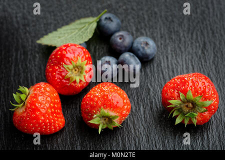 Le fragole e i mirtilli su sfondo nero Foto Stock