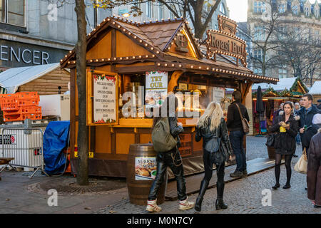 La gente passa un cibo in stallo nel trafficato mercato di Natale, Sheffield, Regno Unito Foto Stock