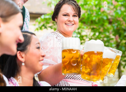 La cameriera che serve birra nel giardino della birra Foto Stock