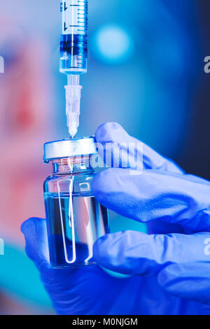 Medico redazione soluzione dal flacone di vaccino e il riempimento della siringa per iniezione di vaccinazione del paziente in clinica medica, la sanità e la medicina profes Foto Stock