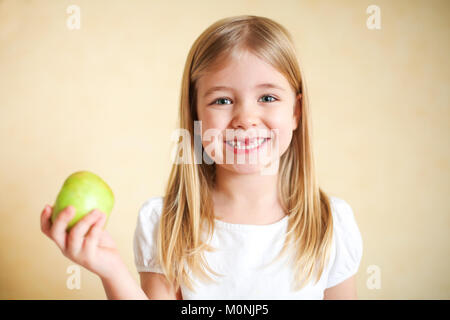 Portreit poco divertente ragazza bionda con mela verde Foto Stock