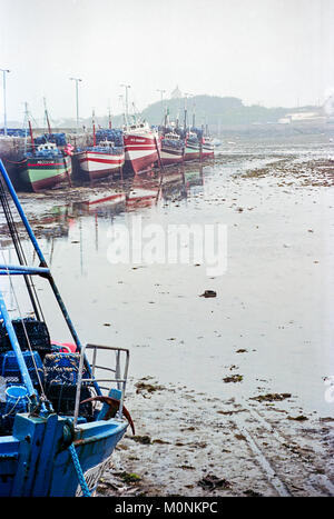 Un giorno di nebbia in Morlaix, Francia. Nel porto di una fila di navi per la pesca a strascico sono ormeggiati alla banchina del porto con la bassa marea. Foto Stock