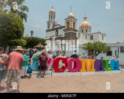 I turisti pongono di fronte al segno colorato Comala un Pueblo Magico la chiesa di Noguerasâˆ'Iglesia de Nogueras in background Colima Messico Foto Stock