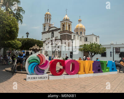 I turisti pongono di fronte al segno colorato Comala un Pueblo Magico la chiesa di Noguerasâˆ'Iglesia de Nogueras in background Colima Messico Foto Stock