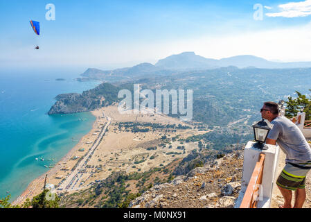 L uomo è guardando Tsampika baia dal balcone sull' isola di Rodi, Grecia Foto Stock