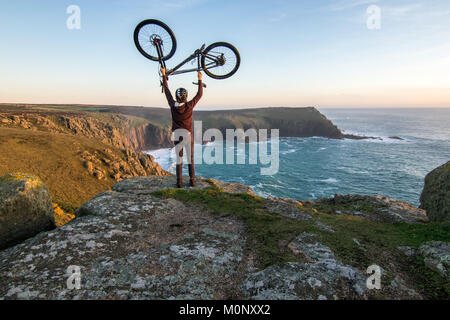 In mountain bike sulle falesie sopra Porthgwarra al tramonto Foto Stock