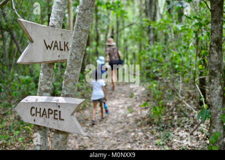 Madre e figlia camminando sulla figliata di foglia percorso con indicazioni a piedi e la cappella in primo piano, Herveys patrimonio di gamma camere di tè, Queensland, Australia Foto Stock